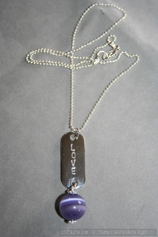 NA028 Purple love: Halsband med stansad tag med texten LOVE och en lila cateye prla...finns att kpa hos Studio Mini SLDFr att se en strre bild, klicka p denna lnk.